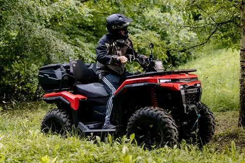 Vozač na CFMOTO quadu u zelenom šumskom terenu