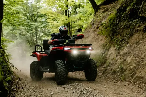 Vozač na CFMOTO quadu kroz šumski teren